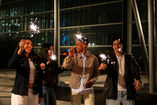 Diverse young friends celebrating a special occasion with sparklers outdoors at night