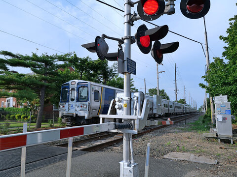 Commuter train at level crossing with red lights on