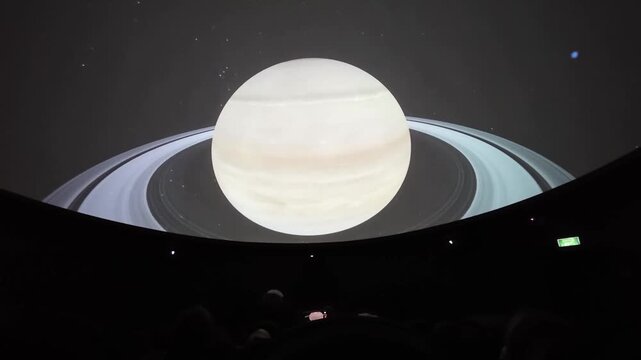 Immersive planetarium dome projection showing planet Saturn, stars constellation map and deep space universe exploration.