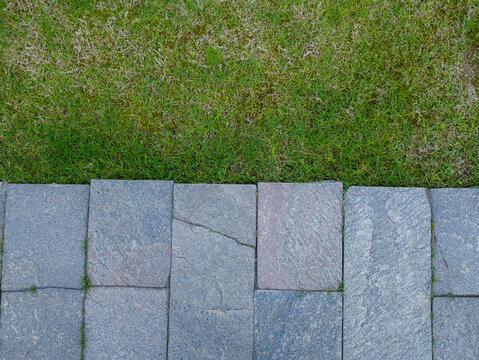 Stone stepping stones path on green grass lawn in garden background