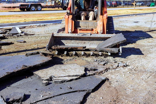 Construction equipment operates on work site to remove asphalt during repair parking lot