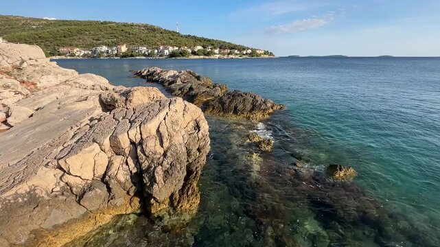 Enjoying a sunny day by the clear water near rocky shores in a coastal area in Croatia during midday