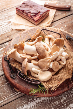 Freshly harvested oyster mushrooms and cured pork belly on a rustic wooden table