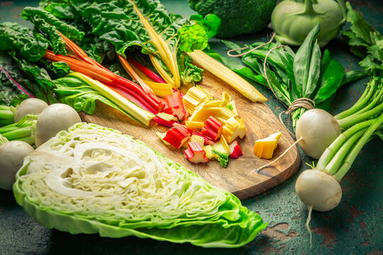 Fresh colorful vegetables on wooden cutting board with green background