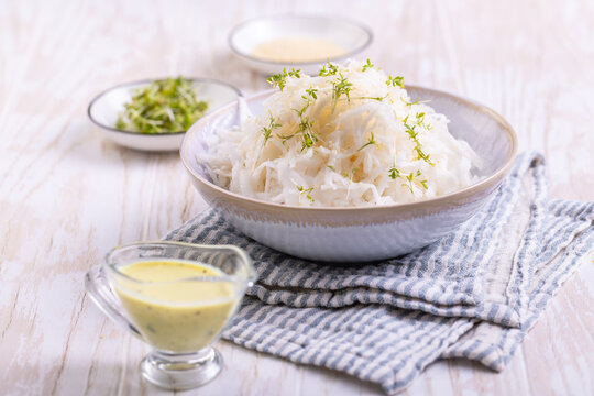 Freshly grated kohlrabi salad with herbs and creamy dressing on a wooden table