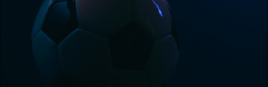 Rotating soccer ball close up on dark blue background
