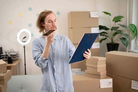 Starting an SME, male small business entrepreneur using smartphone packaging box in online store. SME, small business idea and ecommerce