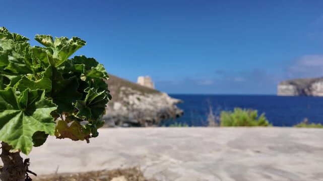 Low angle view of the Xlendi Tower standing against the azure sea and rugged coastline, creating a stunning contrast, Xlendi, Munxar, Malta. High quality 4k footage