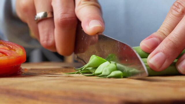 Hands Chopping Fresh Green Beans on a Wooden Cutting Board