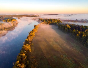Obraz premium Misty Winding River Flowing Through Autumn Forest at Sunrise