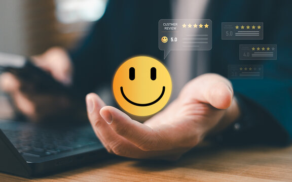 Businessperson holding yellow smile face icon with 5 star rating customer review. Concept of client satisfaction, user experience evaluation, service quality and feedback