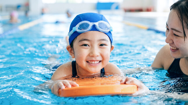 スイミングスクールでコーチから水泳を教わる小学生の子ども