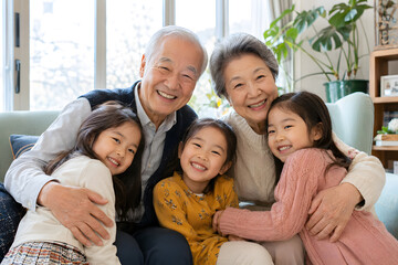 Obraz premium Asian grandparents embracing their three granddaughters at home