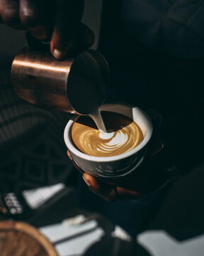 Latte art being poured with tree in background 