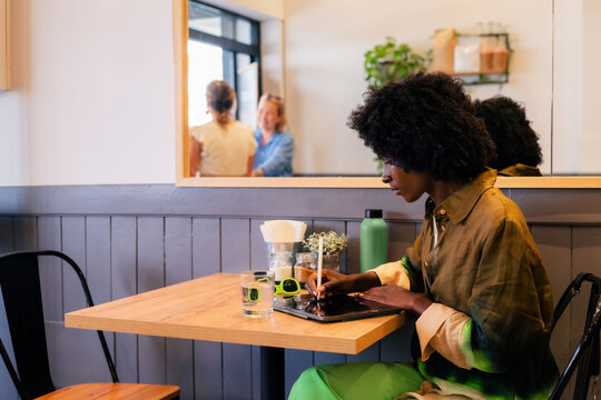 Focused woman working at cafe using tablet computer 