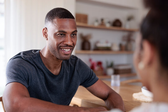 Man talking with woman at table in home setting