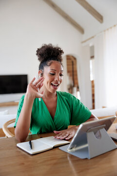 Woman waving during video call while taking notes