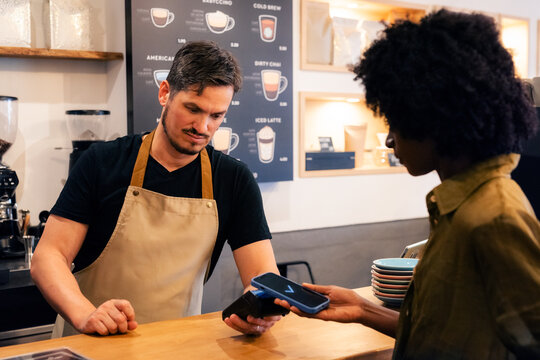 Barista using POS terminal to accept payment 