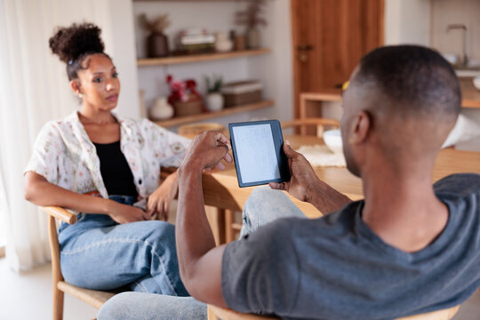 Couple relaxing at home, man reading on e-reader