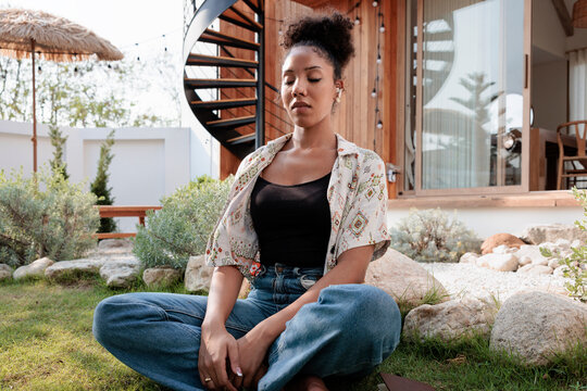Woman meditating outdoors in modern backyard