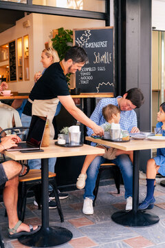 Waiter serving guests at cafe 