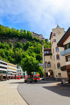 Scenic vertical view of the town hall building and pedestrian street with Vaduz Castle on a forested hill above in Liechtenstein