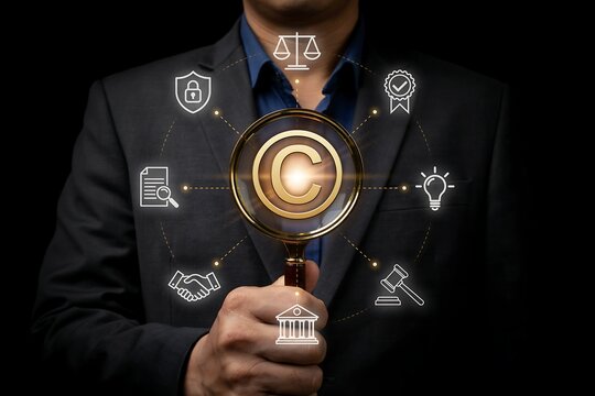 Businessman holding a magnifying glass over a copyright symbol with legal icons around him