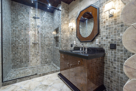 A stylish bathroom featuring tiled walls, a spacious shower area, and a sleek vanity. Soft lights add warmth to the space