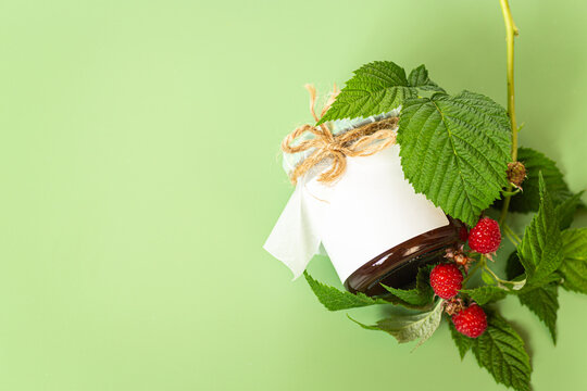 Homemade raspberry jam jar with blank label and fresh berries