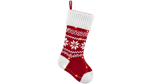 Red knitted christmas stocking with white snowflake pattern and small glowing fairy lights