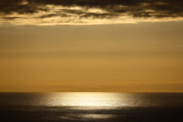 Golden sunset over the Atlantic Ocean beneath dramatic clouds © Gabriela