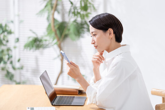 スマホを見て悩む女性