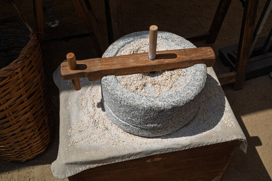 Traditional manual stone rotary mill grinding grain into flour
