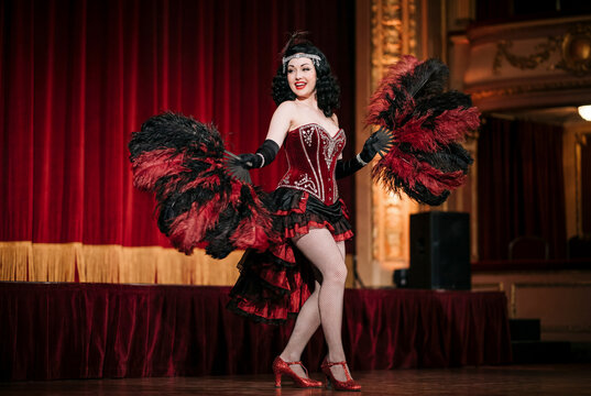 Showgirl performing burlesque with feather fans on stage