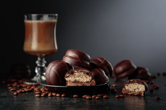 Chocolate dessert and cup of coffee with cream on a black table.