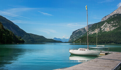pleasure boat moored to a pontoon on a lake in the Dolomites with mountain background Molveno lake Trentino Alto Adige Italy © coco