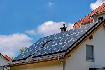 Fototapeta premium Sustainable solar panels array on a residential house roof with blue sky
