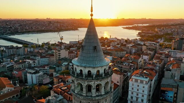 Istanbul Galata Tower at sunset aerial drone shot. Panoramic view of historic landmark, golden hour sky and scenic Golden Horn background.
