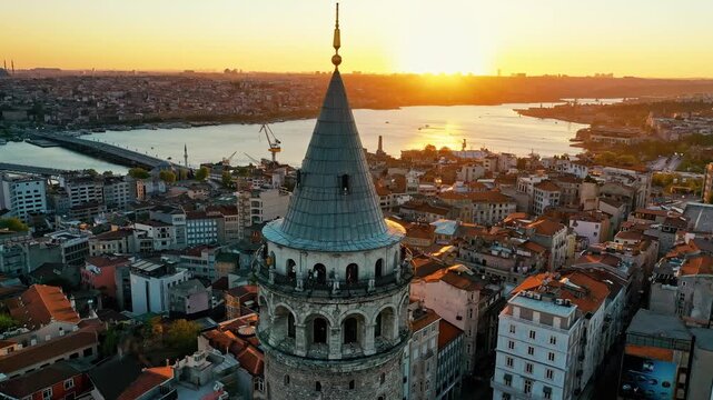 Istanbul Galata Tower at sunset aerial drone shot. Panoramic view of historic landmark, golden hour sky and scenic Golden Horn background.
