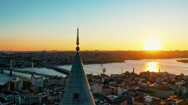 Istanbul Galata Tower at sunset aerial drone shot. Panoramic view of historic landmark, golden hour sky and scenic Golden Horn background.
