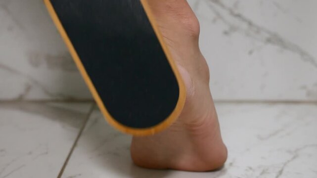 Close-up of female foot exfoliation using foot file to remove dry skin and callus from heel