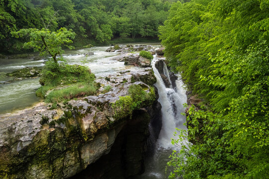  Powerful waterfall in Martvili Canyon surrounded by lush green forest, Samegrelo, Georgia.
