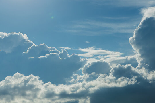 White fluffy clouds scattered across a bright blue sky with soft sunlight illuminating the scene, creating a serene and tranquil atmosphere in the daytime