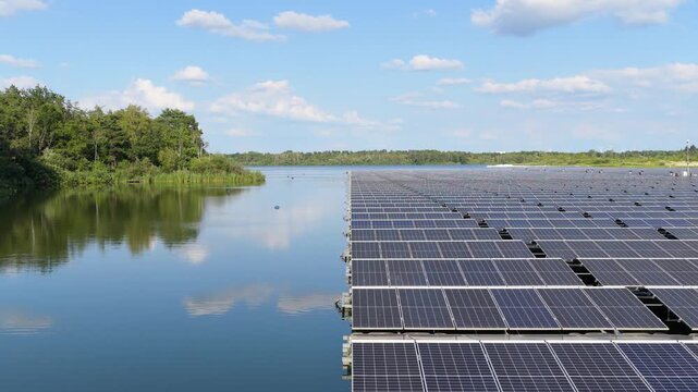 Aerial drone view of a floating solar panel farm on a calm lake surface. Modern green technology facility producing clean renewable energy on water.