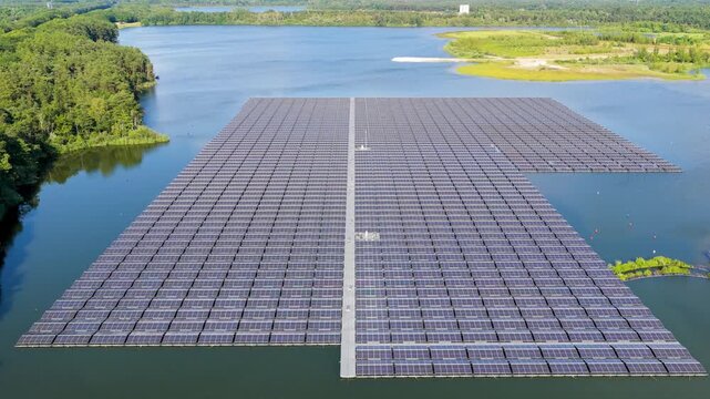 Aerial drone view of a floating solar panel farm on a calm lake surface. Modern green technology facility producing clean renewable energy on water.