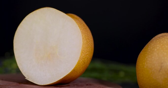 A golden pear on a cut tree, this ripe pear object is represented as thin slices on a brown wood background.