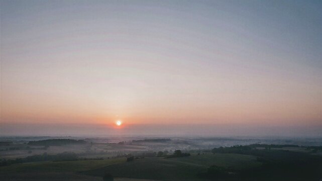 Sunrise over a scenic rolling landscape with fog covering the valley