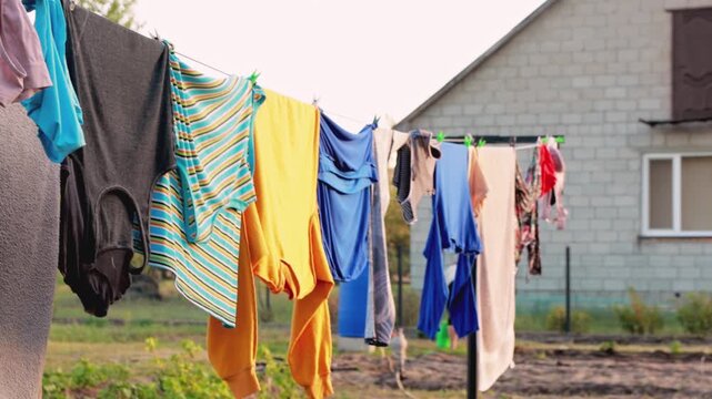 Colorful laundry hanging on clothesline to dry outdoors in backyard. Clean clothes drying in wind near house, domestic chores, housework and eco-friendly lifestyle concept