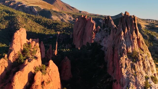 Aerial view of Garden of the Gods park rock formation landscapes with sunrise alpenglow light during autumn season in Colorado Springs, Colorado with mountains in background - 4K Drone