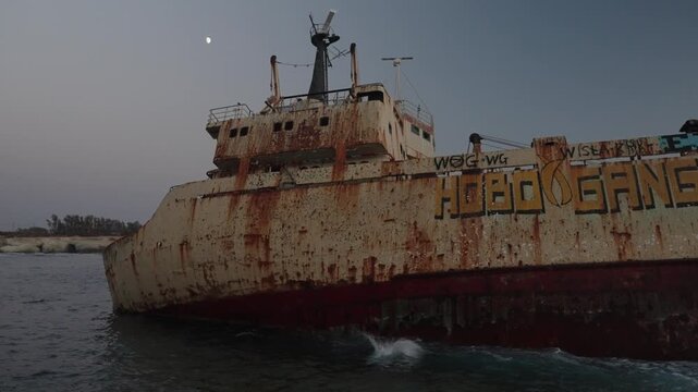 Rusty old shipwreck near the coastline on sunset
